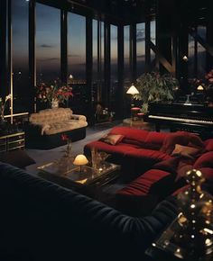 a living room filled with lots of furniture next to tall windows at night time,