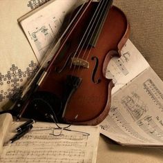 an old violin sitting on top of sheet music