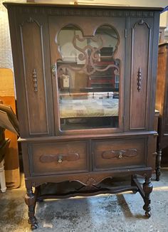 an antique china cabinet with glass doors and drawers on the bottom, sitting in a room