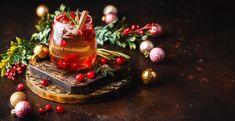 a glass filled with liquid sitting on top of a wooden table next to christmas decorations