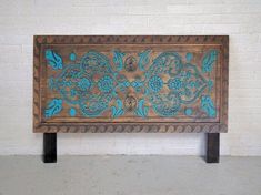 an old wooden bench with blue paint on the top and bottom, sitting against a white brick wall