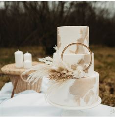 a wedding cake sitting on top of a table covered in white frosting and feathers