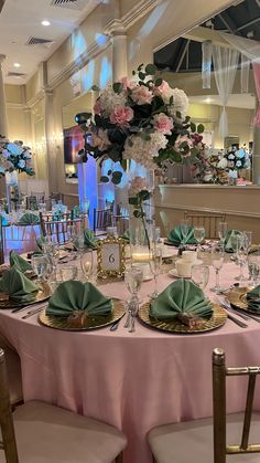 the table is set with pink and green plates, silverware, and flowers in vases