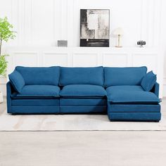 a blue sectional couch sitting on top of a rug in front of a white wall