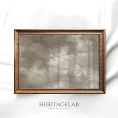 an empty wooden frame hanging on a white wall with the words heritage lab written below it