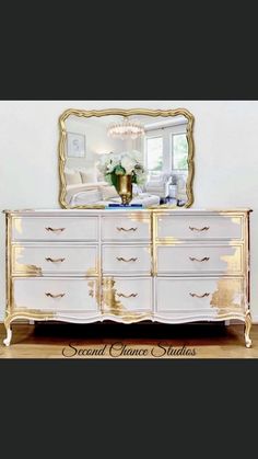 a white and gold dresser with a mirror above it