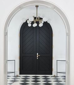 a black and white checkered floor in front of a door with two lights on it