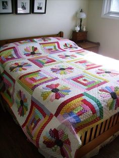 a bed with a quilt on top of it in a room next to a window