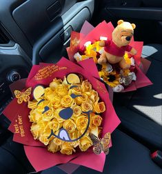 two winnie the pooh bouquets sitting on top of a car dashboard next to a teddy bear