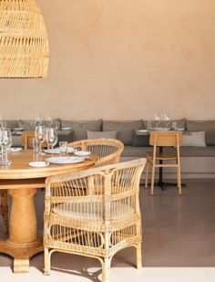 a dining room with wicker furniture and table set for six people, in front of a beige wall