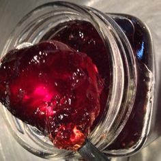 a jar filled with jam sitting on top of a metal table next to a spoon