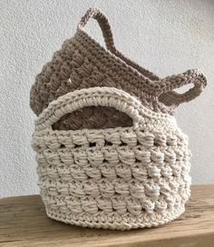 two crocheted baskets sitting on top of a wooden table