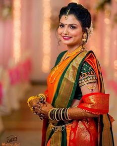 a woman in an orange and green sari with her hands on her hip smiling