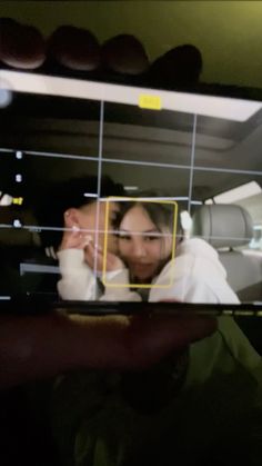 a man and woman are seen through the screen of a cell phone while sitting in a car