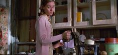 a woman standing in a kitchen preparing food on top of a wooden stove burner