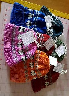 several knitted hats are displayed next to a ruler