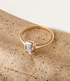 a close up of a gold ring with a stone in the middle on a rock