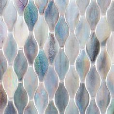 a close up view of a glass mosaic tile wall with wavy lines and leaves on it