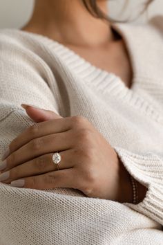 a woman wearing a white sweater with a diamond ring on her left hand and the other hand wrapped around her shoulder