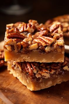 two pieces of pecan bar sitting on top of a wooden cutting board