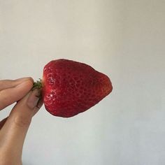 a person holding a strawberry in their hand