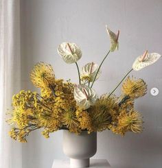 a white vase filled with lots of yellow flowers