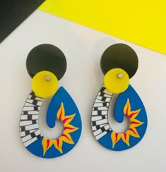 pair of colorful earrings on white surface with yellow and blue background