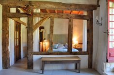 a bed sitting under a mirror next to a wooden bench in front of a doorway