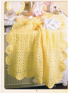 a yellow crocheted blanket sitting on top of a table next to other items