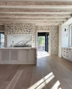 an empty kitchen with stone walls and flooring in the center, along with large windows