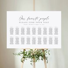 the seating chart for an event is displayed on top of a easel with greenery