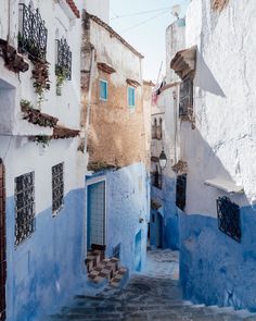 an alley way with blue buildings and steps