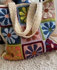 a multicolored crocheted bag sitting on top of a white rug next to a stuffed animal