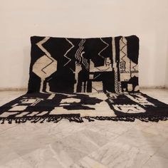 a large black and white rug on top of a tile floor next to a wall