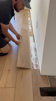 a man that is kneeling down on the floor with some wood in front of him