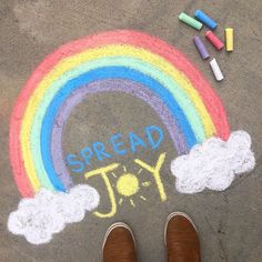 someone's feet standing in front of a sidewalk with chalk crayons on it