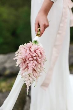 a bride holding a bouquet of pink flowers