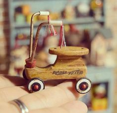 a small wooden toy car sitting on top of someone's finger