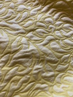 an intricately designed yellow and white bedspread is seen in this close up photo