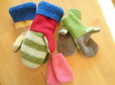 three knitted mittens and gloves laying on a wooden floor next to each other