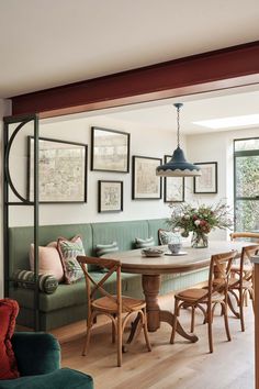 a dining room table with chairs and pictures on the wall