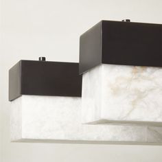 two black and white square lights hanging from a ceiling fixture in a room with marble walls