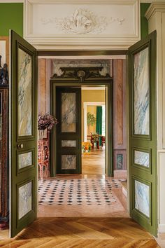 an open door leading to another room with green walls and white trim on the ceiling