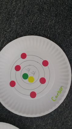 two paper plates sitting on top of a black table covered in white and red circles