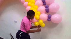 a man is decorating some balloons on the wall in an office building with pink, yellow and purple colors