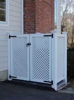 a white gate sitting in front of a house next to a brick wall and window