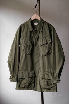 an army green jacket hanging on a clothes rack