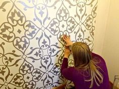 a woman painting a wall with stencils on it