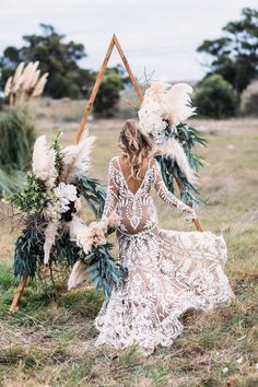 a woman in a white lace dress with feathers on her head is holding a floral arrangement