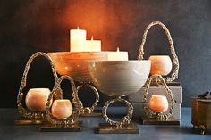 an assortment of candle holders and candles on display in front of a black background with gold accents